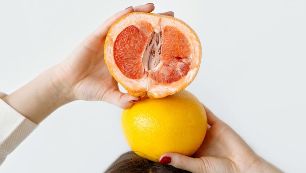 Woman holding orange above her head, visually representing affordable glow essentials.