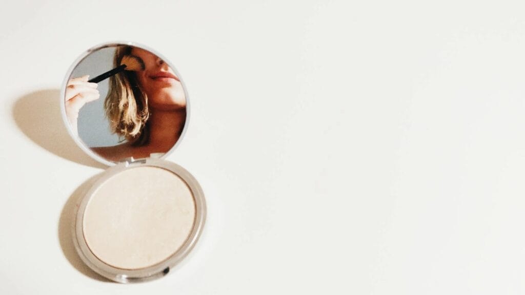 Girl in the mirror putting makeup on.