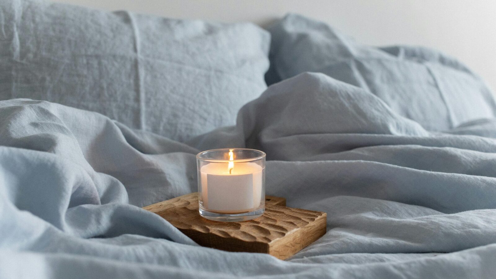 candle on bed, representing wellness habits for glowing skin