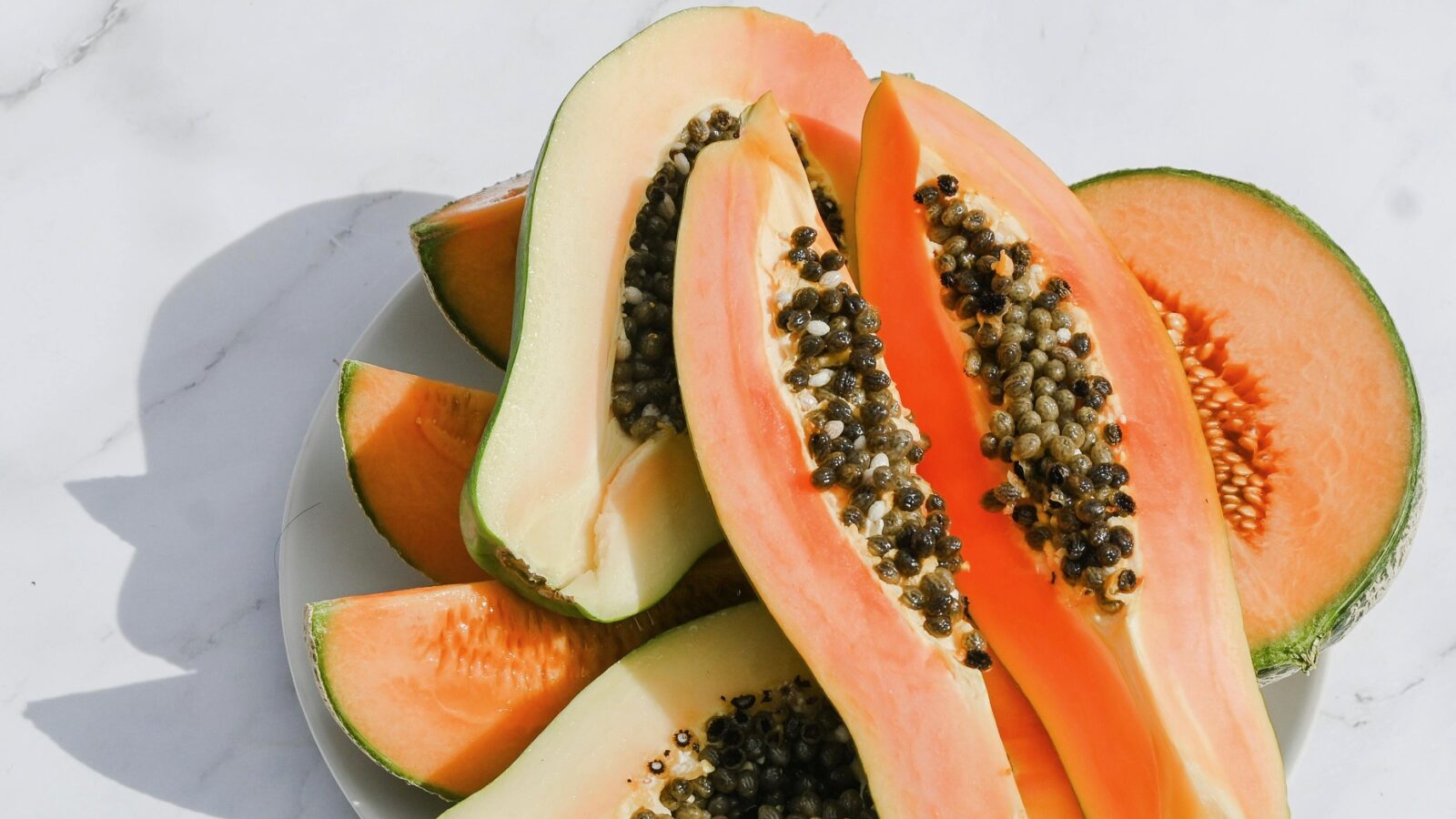 Papaya slices on marble representing best gentle exfoliants for glowing skin