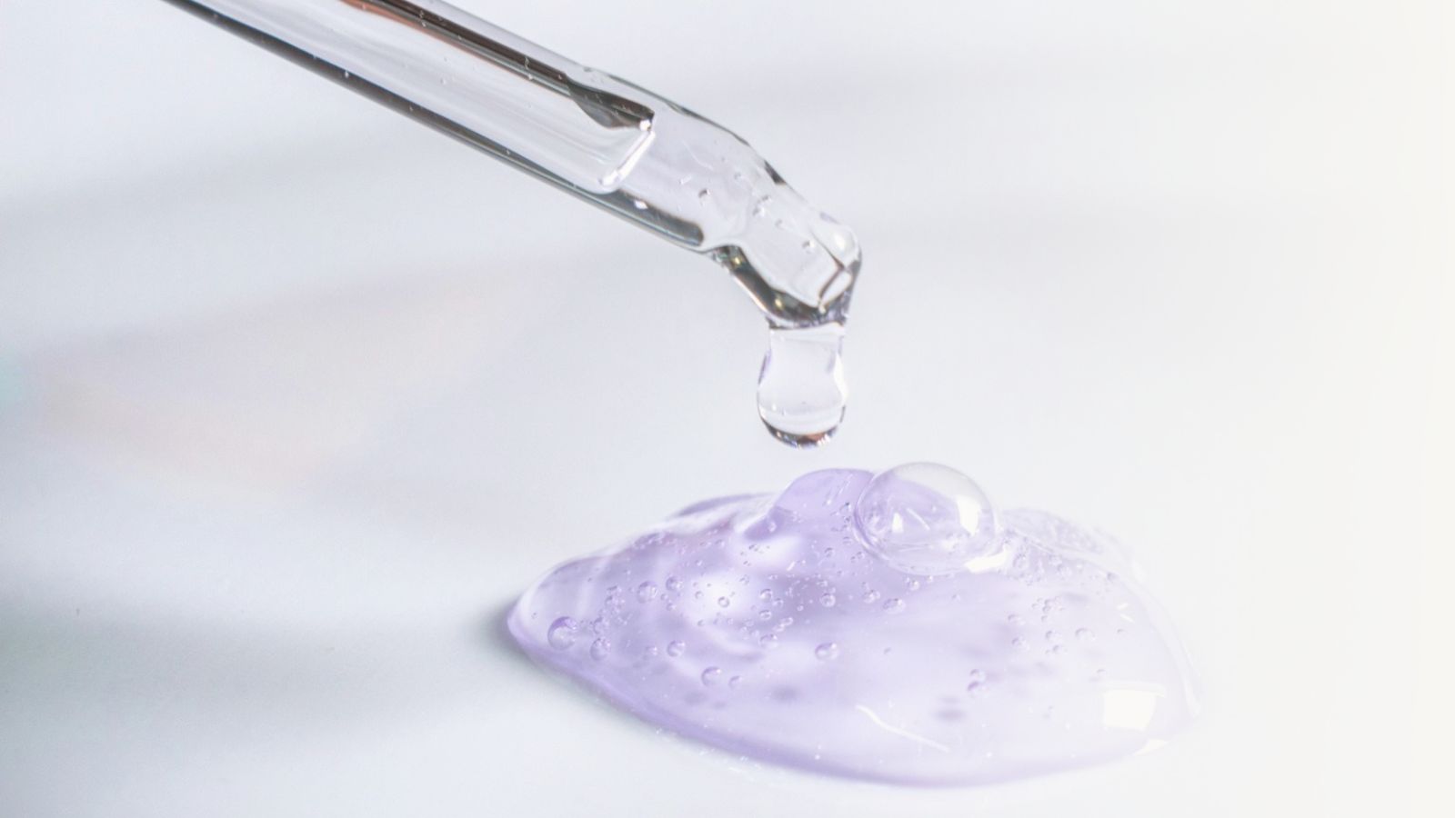 Clear dropper dispensing a lilac gel texture.