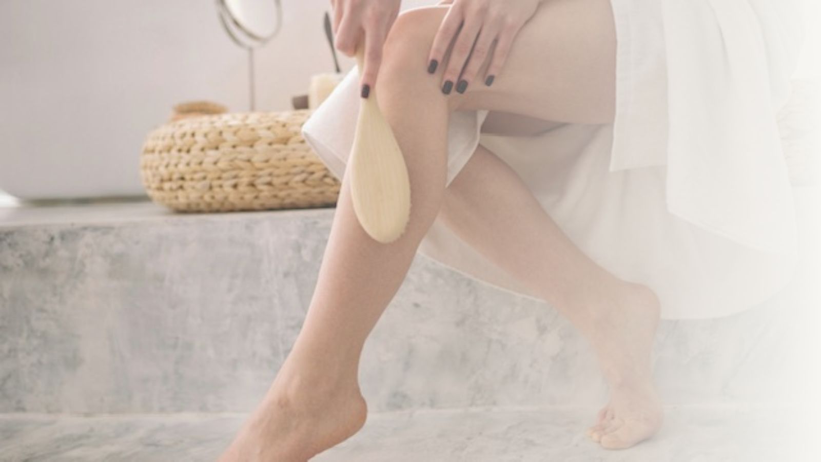 Woman dry brushing legs in bathroom -- part of night skincare routine.