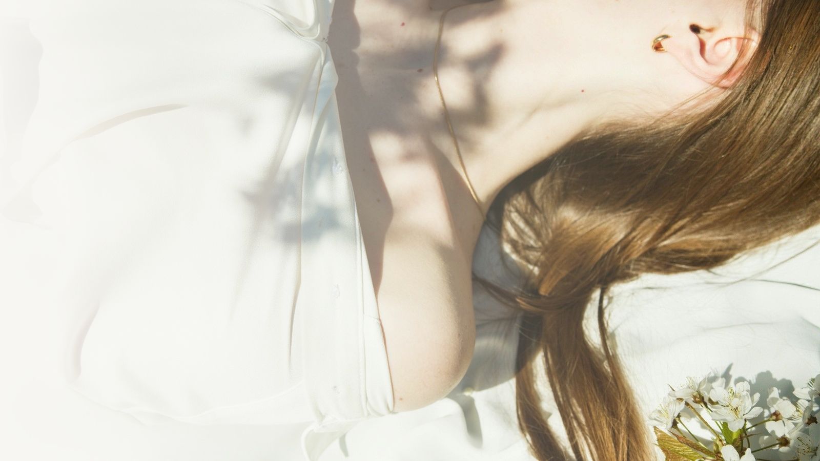 Soft light and shadow on a woman's collarbone in a relaxed, natural setting