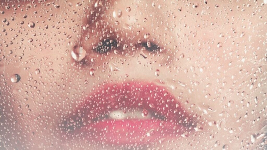 Water droplets and woman's face representing Makeup That Lasts in Humidity Without Looking Heavy.
