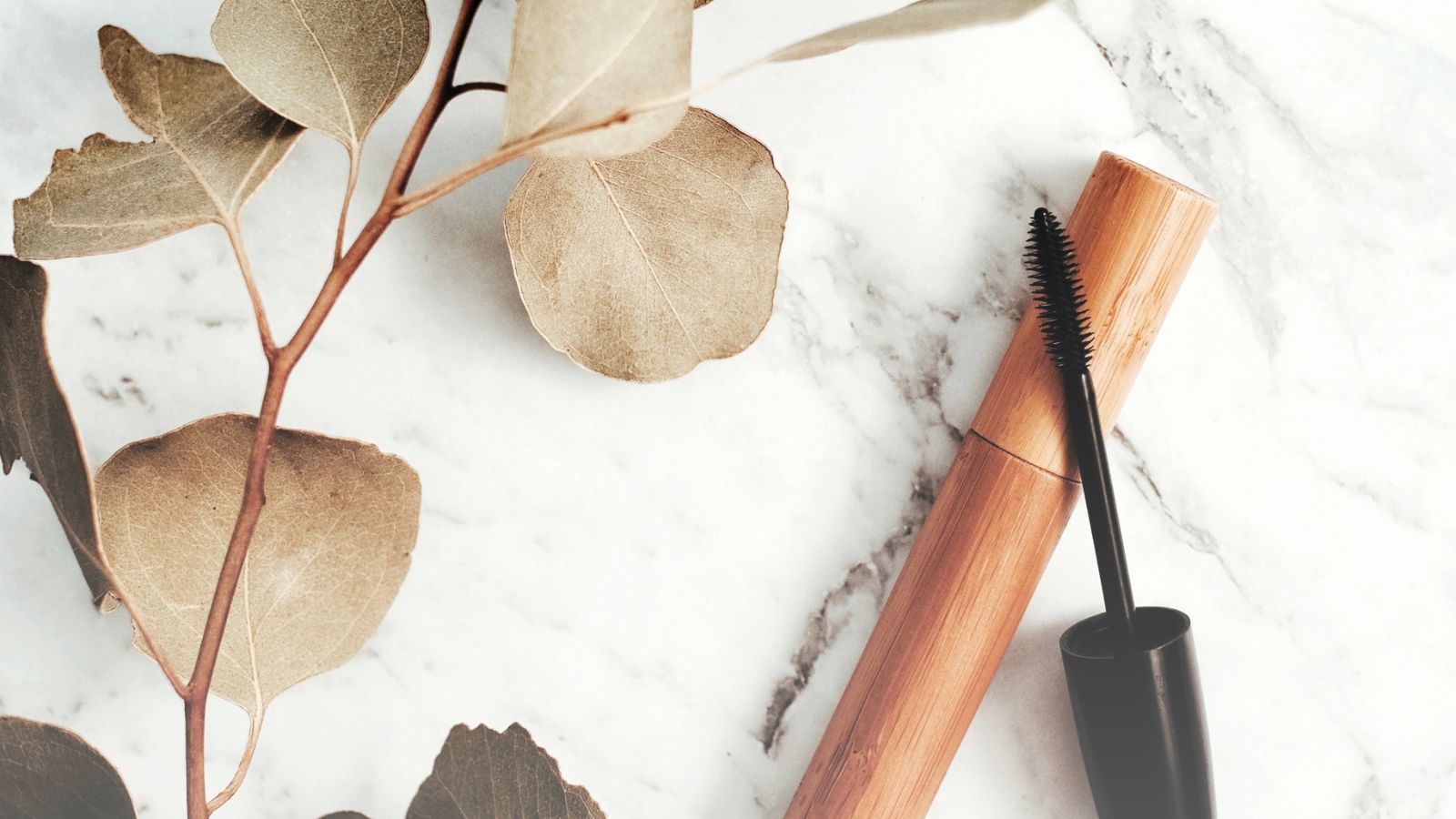 Mascara brush next to a dry branch — representing makeup for barrier-stressed skin.