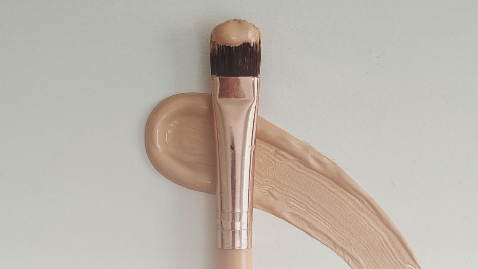 Skin tint vs. tinted moisturizer visual of smudged brush stroke.