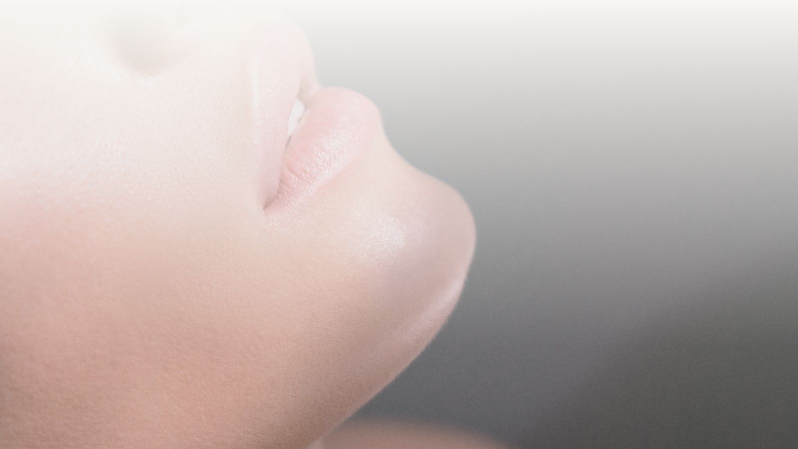 Close-up of glowing skin and lips in soft light.