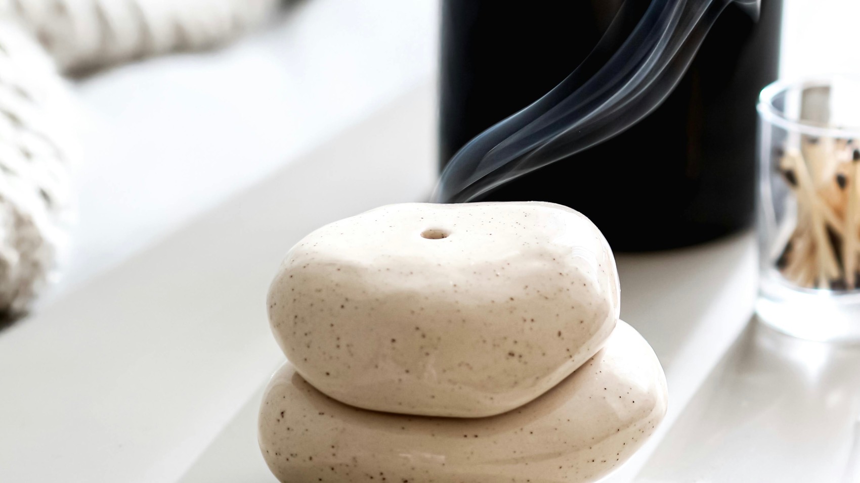 Stacked stones with smoke, representing wellness rituals.