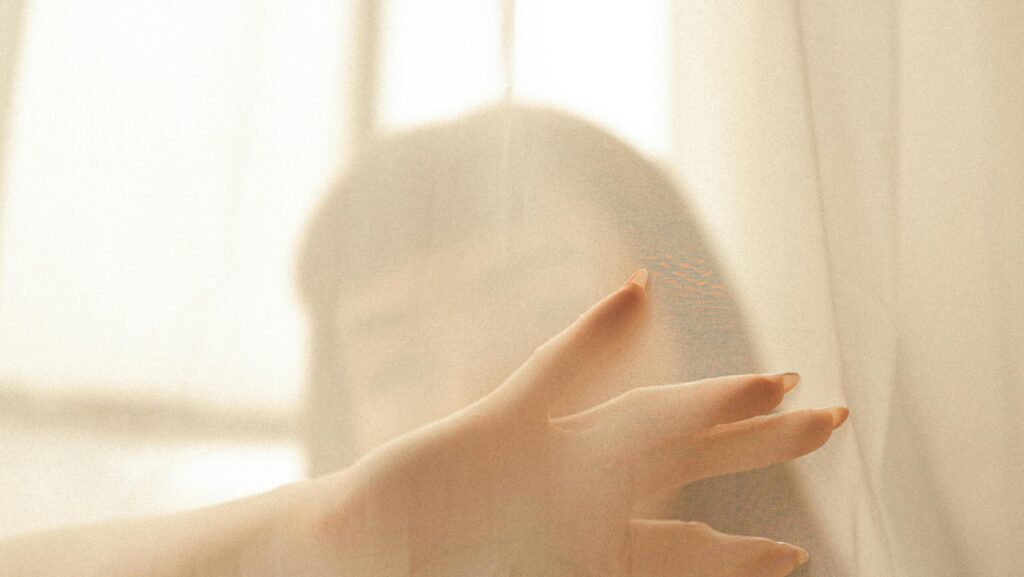 Woman behind a vail visually representing setting spray vs hydrating mist for glowing makeup