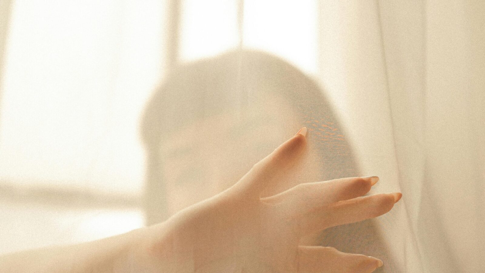 Woman behind a vail visually representing setting spray vs hydrating mist for glowing makeup