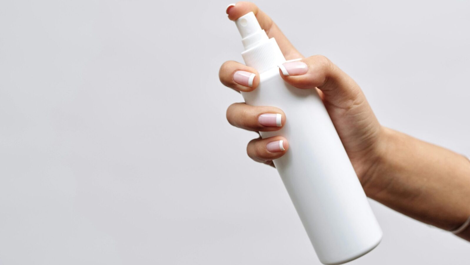 Hand holding a spray bottle representing hydrating toners & mists for dry skin.
