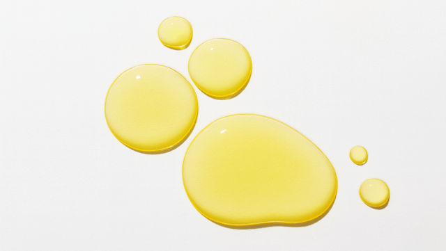 Best face oils for changing season image represented by closeup of oil drops on white surface.