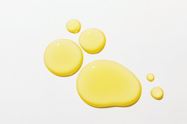 Best face oils for changing season image represented by closeup of oil drops on white surface.