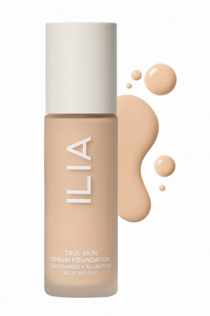 ILIA Best Dewy Foundation cream product bottle with makeup spill behind on white background.