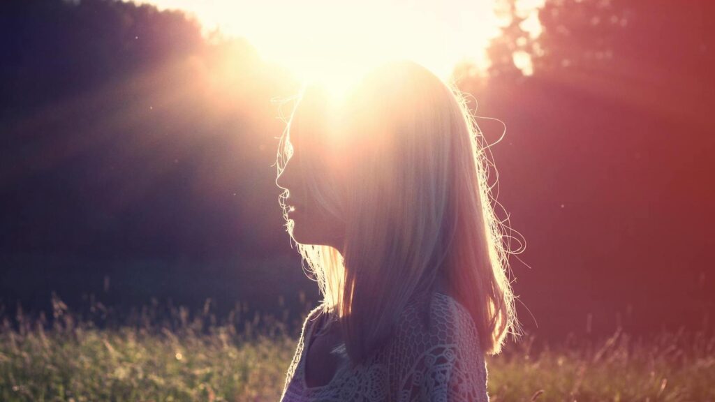 Evening makeup shades for glowing skin represented by woman's silhouette against setting sun.