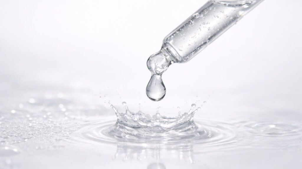 Best essences and serums for tight skin represented by pipette dripping clear water.