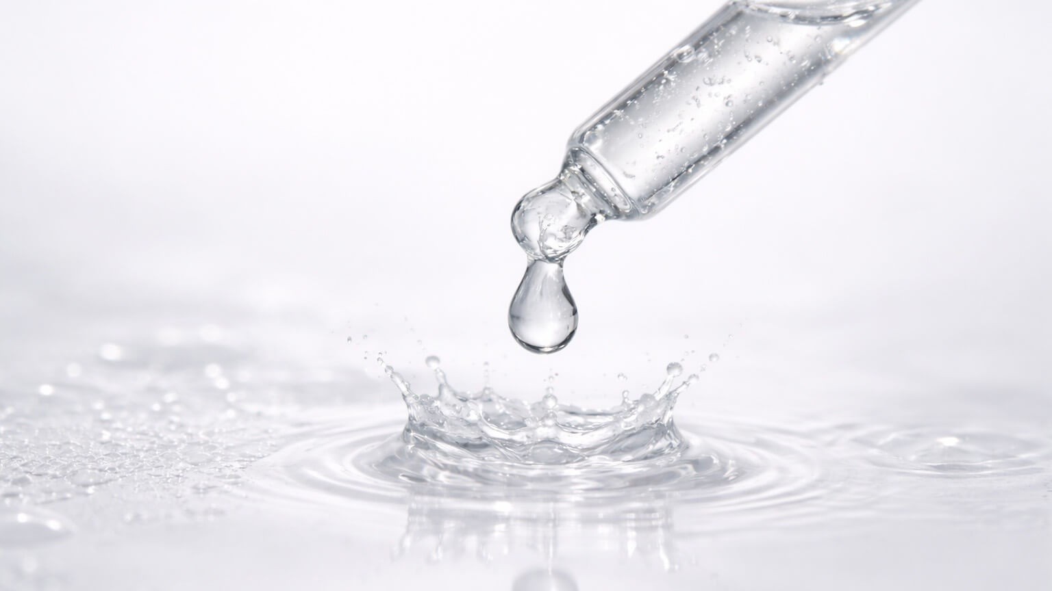Best essences and serums for tight skin represented by pipette dripping clear water.