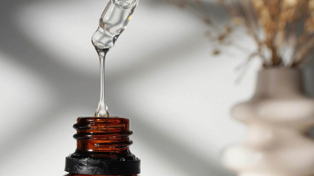 Hydrating serums for dehydrated skin that still feels dry represented by pipette dripping clear water.