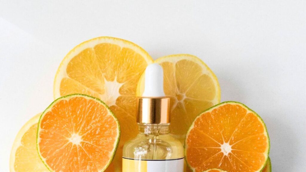 Dropper bottle of citrus serum surrounded by sliced oranges, representing the best vitamin c serums for dull, uneven skin tone.