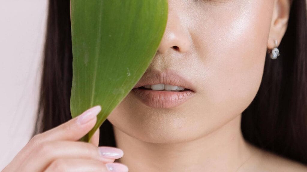 Lightweight hydration routine for oily and combination skin represented by woman's face hiding behind leaf.