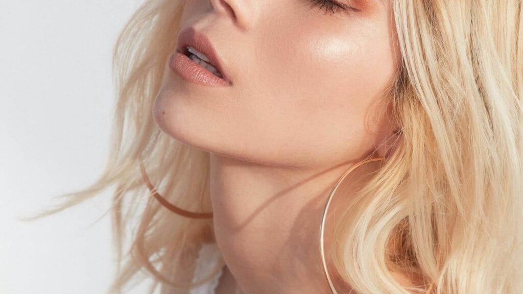 Close-up of blonde woman with dewy skin and natural shimmer, illustrating why glowy makeup looks flat in daylight.