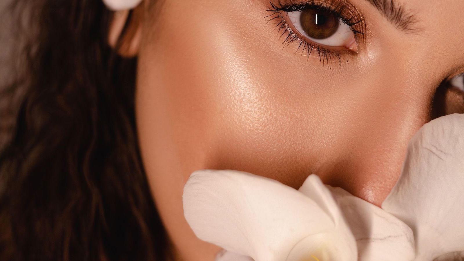 Best liquid highlighters that melt into the skin illustrating by woman's flawless cheek close up.